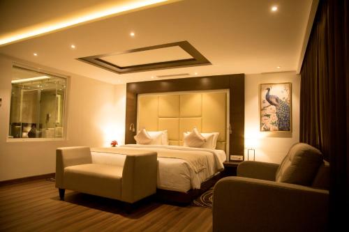 S Hotels Chennai في تشيناي: غرفة نوم بسرير كبير وكرسيين