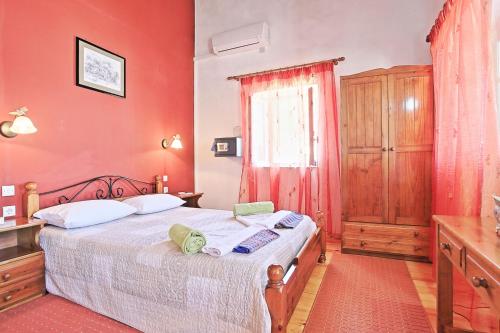 a bedroom with a bed with red walls and a window at Olgas Cottage: Stone house on the beach in Kéntroma