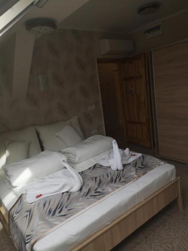 a unmade bed with white towels on top of it at Szent István Wellness Panzió in Makó