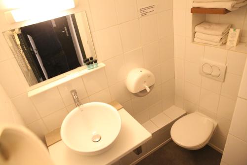 a white bathroom with a sink and a toilet at Arnaud Bernard Hôtel in Toulouse