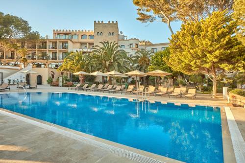 a pool with chairs and umbrellas in front of a building at Secrets Mallorca Villamil Resort & Spa - Adults Only (+18) in Paguera