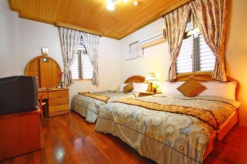 a bedroom with two beds and a flat screen tv at Yilan Affectivity in Wujie