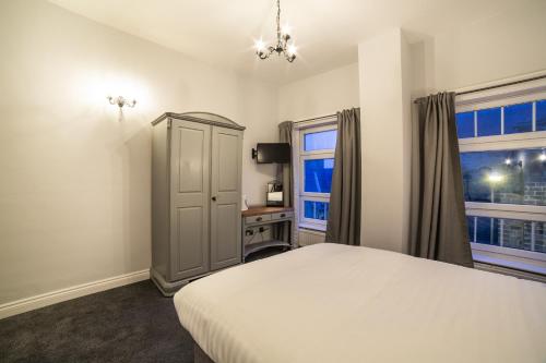 a bedroom with a white bed and a window at Churchill's Hotel in Wombwell