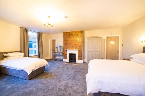 a bedroom with two beds and a fireplace at Churchill's Hotel in Wombwell