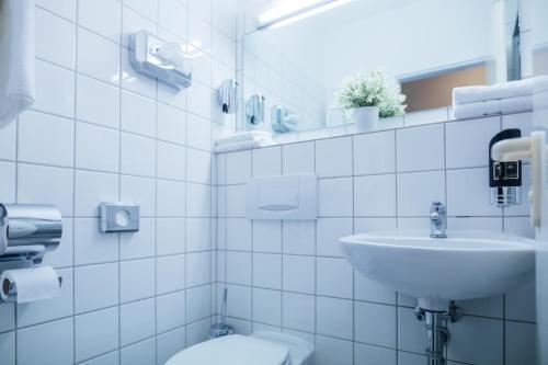 a white bathroom with a sink and a toilet at Hotel CULT Hamburg in Hamburg