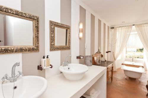 Baño blanco con lavabo y espejo en Oue Werf Country House, en Oudtshoorn