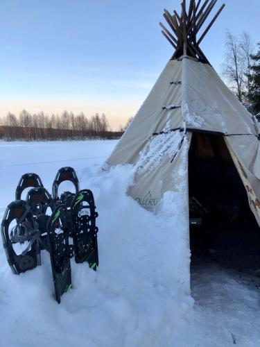 a snowboard and a teepee in the snow at Ollero Eco Lodge (including a glass igloo) in Rovaniemi