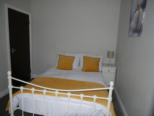a white bed with orange pillows in a bedroom at Cosy two bedroom apartment in Bishop Auckland