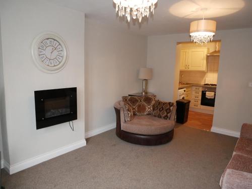 a living room with a chair and a clock on the wall at Cosy two bedroom apartment in Bishop Auckland