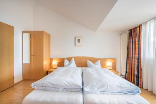 a bedroom with a large white bed with two lamps at Appartementhotel Röhrenbach in Immenstaad am Bodensee