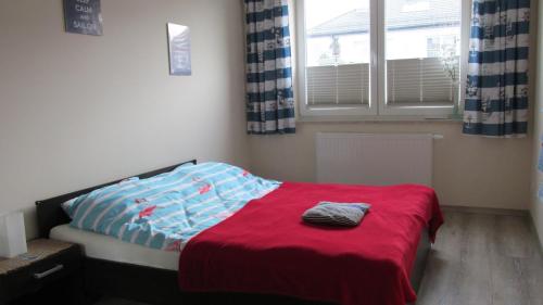 a bedroom with a bed with a red blanket and a window at Gdynia, odpocznij od zgiełku in Gdynia