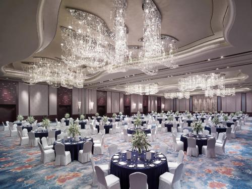 a banquet hall with tables and chairs and chandeliers at Shangri-La Qingdao - May Fourth Square in Qingdao