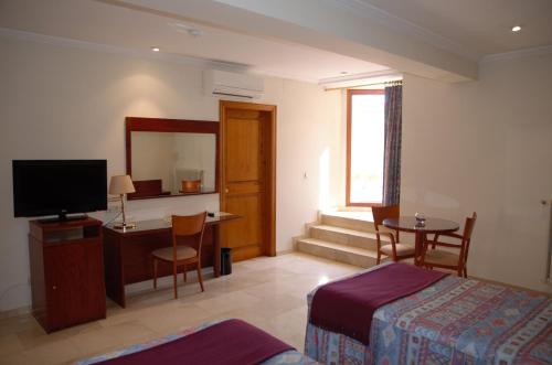 Schlafzimmer mit einem Bett, einem Schreibtisch und einem TV in der Unterkunft Hotel Suís in San Celoni
