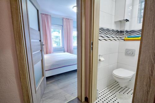 a small bathroom with a toilet and a bed at Apartament Gałązka Jabłoni in Duszniki Zdrój