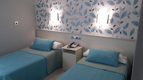 2 camas individuales en una habitación de color azul en Hostal La Despensa de Extremadura en Plasencia