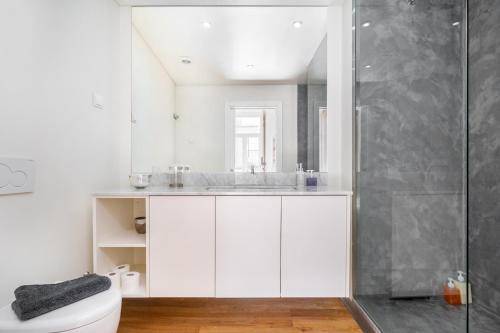 uma casa de banho branca com um chuveiro e um WC. em WHome | Alcântara Smart Studio em Lisboa