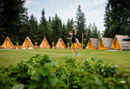 a man standing in a field with a frisbee at Glamping FOREST EDGE in Kamnik