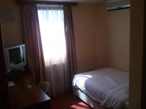 a bedroom with a bed and a window with a television at Hotel Srbija in Vršac