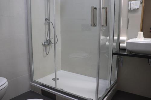 une douche avec une porte vitrée à côté d'un lavabo dans l'établissement Hotel Belém Tejo - Setubalense, à Lisbonne