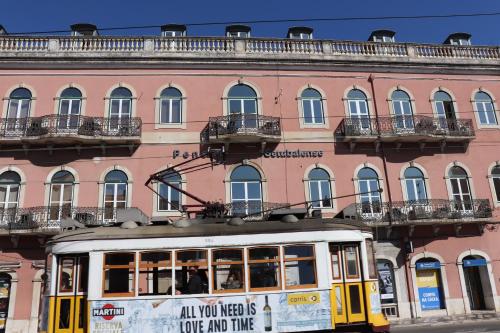 a trolley car in front of a pink building at Hotel Belém Tejo - Setubalense in Lisbon
