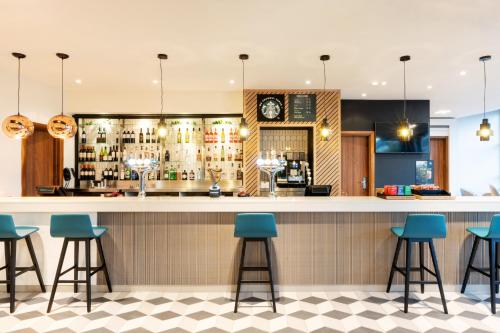 a bar in a restaurant with blue stools at Holiday Inn Stevenage by IHG in Stevenage