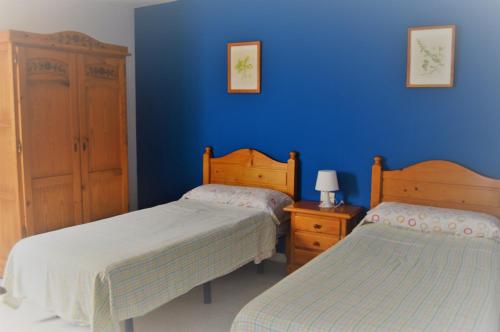 1 dormitorio con 2 camas y pared azul en Apartamentos herederos Lm, en Caleta de Sebo