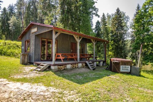 a small cabin with a picnic table in the grass at Kempings Ozolkalns in Cēsis