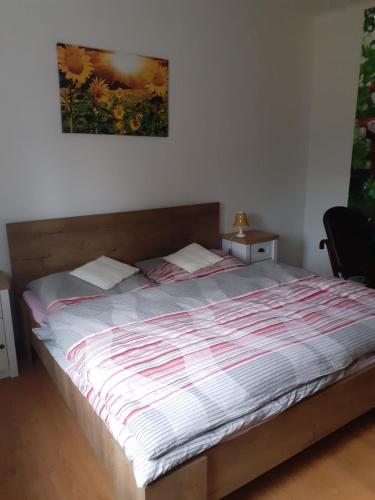 a bed in a bedroom with a picture on the wall at Apartman Ema in Sloup