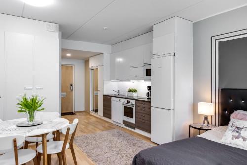 a room with a bed and a table and a kitchen at Trendy Homes Oulu Rautatienkatu in Oulu