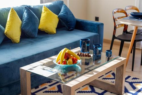 a coffee table with a bowl of fruit on a blue couch at Flamant Rose Appart Hotel in Tangier
