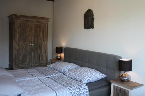 a bedroom with a bed and a cabinet and two lamps at Slapen & Smullen in Swalmen