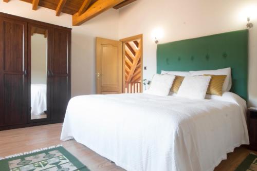 a bedroom with a large white bed with a green headboard at Mortazel River Houses in Montazel