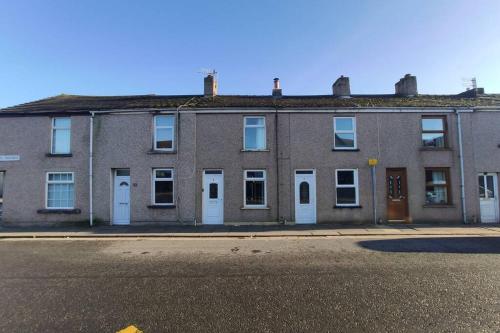 an old brick building with white doors on a street at Unique, cosy, Lake District artist hideaway - 5 bd in Millom