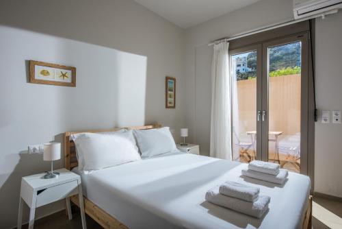 a bedroom with a white bed with towels on it at Caravel Apartments Stalis in Stalida