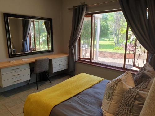 a bedroom with a bed and a desk and a mirror at House Elizabeth in Scottburgh
