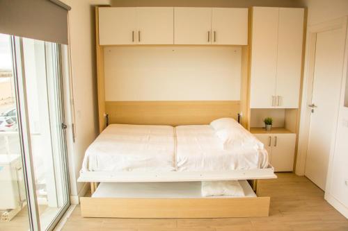 Cette petite chambre comprend un lit avec des draps blancs. dans l'établissement Apartamento Astro, à Quarteira