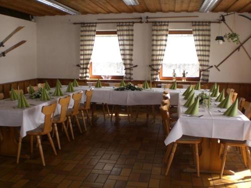 a large room with white tables and chairs and windows at Höhengasthof Wanderheim Nägelehaus in Albstadt