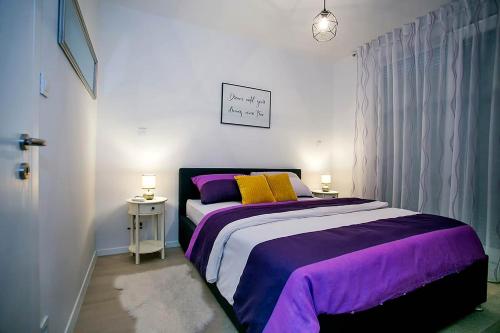 een slaapkamer met een groot bed met paarse en gele kussens bij Apartment Sweet Daisy with parking in Zadar