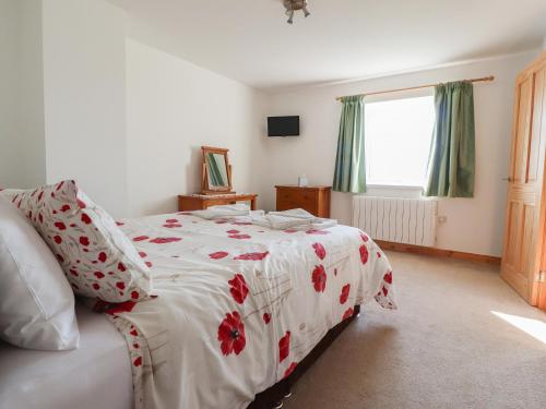 ein Schlafzimmer mit einem Bett mit roten Blumen darauf in der Unterkunft Katy's Cottage in Skipton