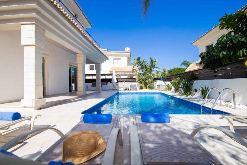 una piscina con mesa y sillas junto a una casa en Villa Malama, en Paralimni