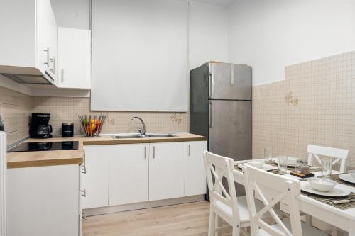 a kitchen with white cabinets and a table with chairs at Alsos Family Apartment in Corfu