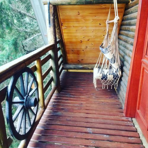 a porch of a cabin with a porch swing at CHALÉ ESTÂNCIA OURO VERDE in Lages