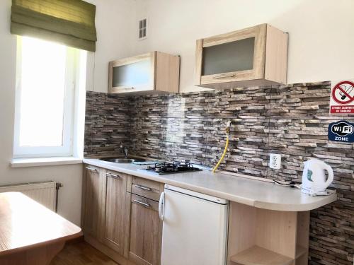 a kitchen with wooden cabinets and a brick wall at АВІА in Uzhhorod