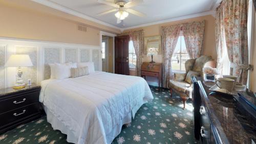 um quarto com uma grande cama branca e uma cadeira em The Ocean Plaza Hotel em Ocean Grove