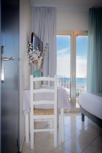 a white room with a white chair and a window at Hotel et Appartements Reine D'Azur in Roquebrune-Cap-Martin