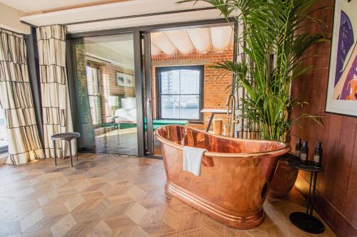 una gran bañera de madera en una habitación con una planta en The Mayson en Dublín