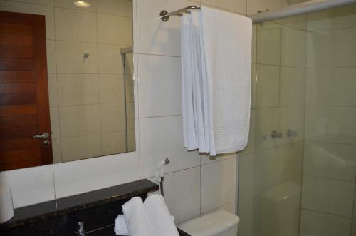 uma casa de banho com um chuveiro, um WC e um espelho. em Hotel La Ville em Sousa