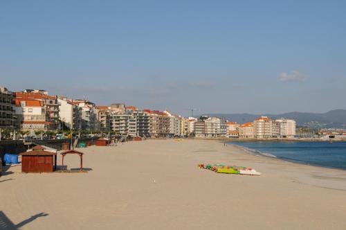 a sandy beach with buildings and condos in the background at apartamento centro sanxenxo con parking gratis in Sanxenxo