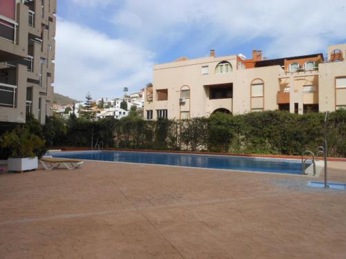 a swimming pool in front of some buildings at Apartamento 1a linea playa com piscina Almuñécar in Almuñécar