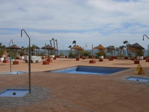a courtyard with a swimming pool and umbrellas at Apartamento 1a linea playa com piscina Almuñécar in Almuñécar
